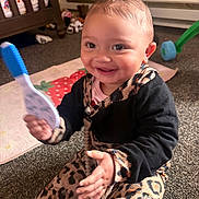 Erin joined the competition — help win amazing prizes! baby, child, smiling, happy, sitting, toy, rattle, nursery, crib, play_mat, carpet, infant, portrait, indoors, clothing, leopard_print, black_outfit, toys, fan, family_home