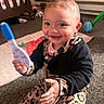 baby, child, smiling, happy, sitting, toy, rattle, nursery, crib, play_mat, carpet, infant, portrait, indoors, clothing, leopard_print, black_outfit, toys, fan, family_home