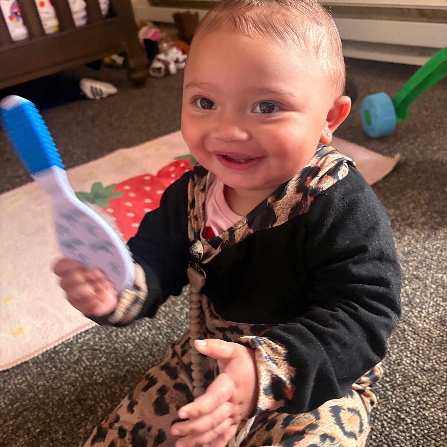 Erin joined the competition — help win amazing prizes! baby, child, smiling, happy, sitting, toy, rattle, nursery, crib, play_mat, carpet, infant, portrait, indoors, clothing, leopard_print, black_outfit, toys, fan, family_home
