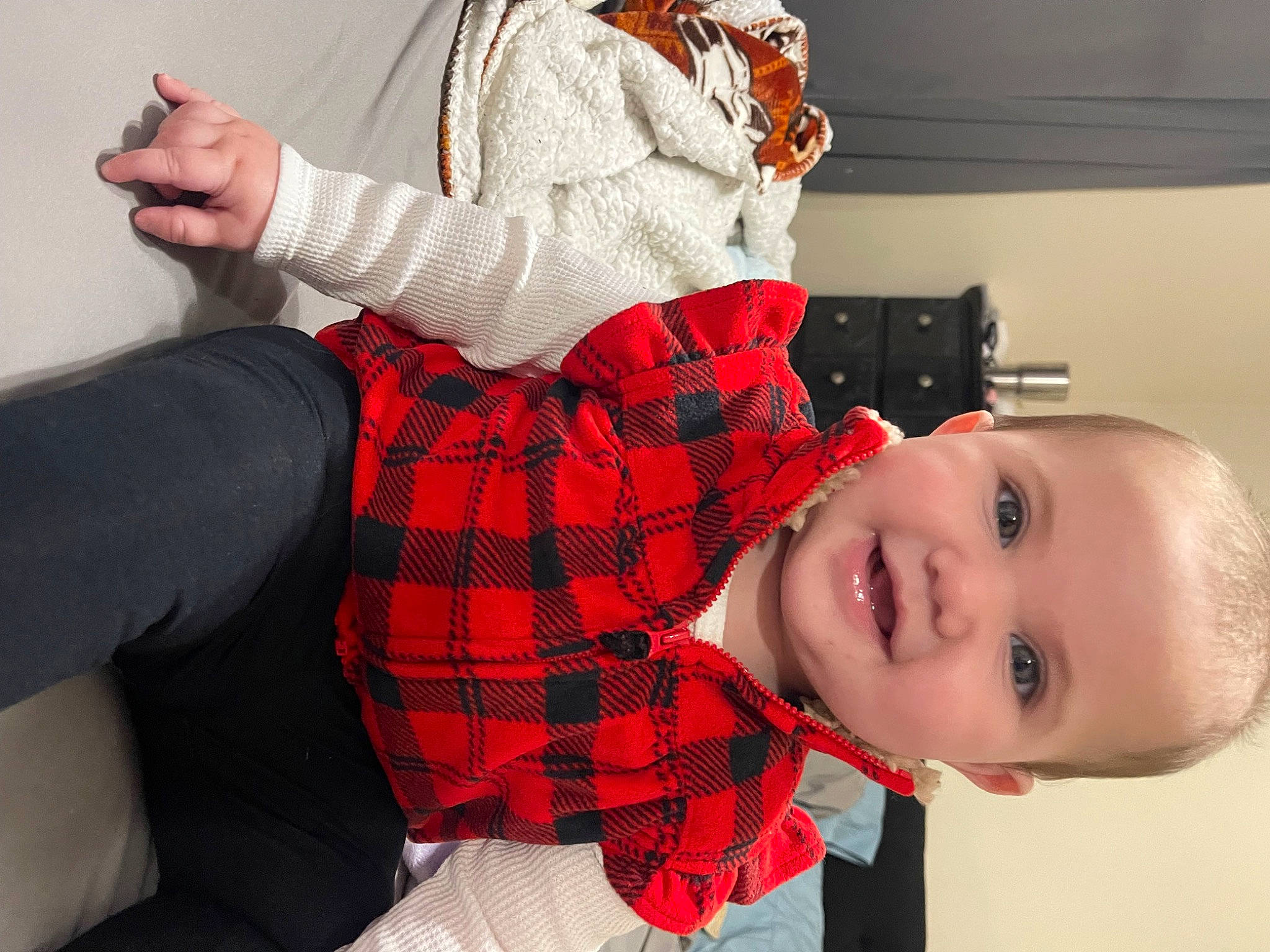 Raelynn is registered to the contest to win money with this photo: baby_toddler_clothing, child, collar, comfort, elbow, happy, human_leg, joy, knee, lap, pattern, person, plaid, red, sitting, sleeve, smile, sock, tartan, textile