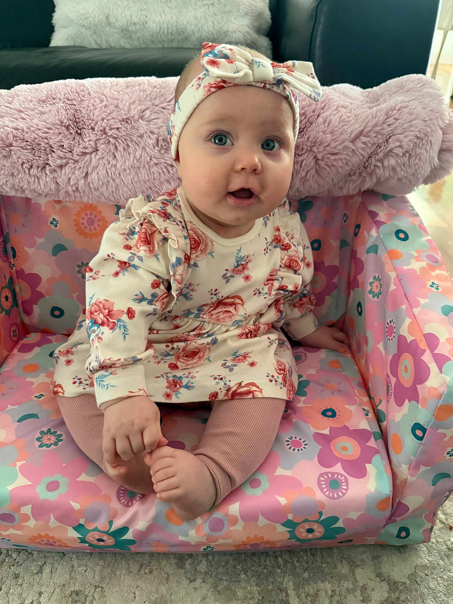 Sara joined the competition — help win amazing prizes! baby, child, infant, sitting, floral_outfit, headband, cushioned_chair, colorful, pattern, foot, hand, indoor, carpet, cute, person, portrait, young_child, clothing, pink, happy