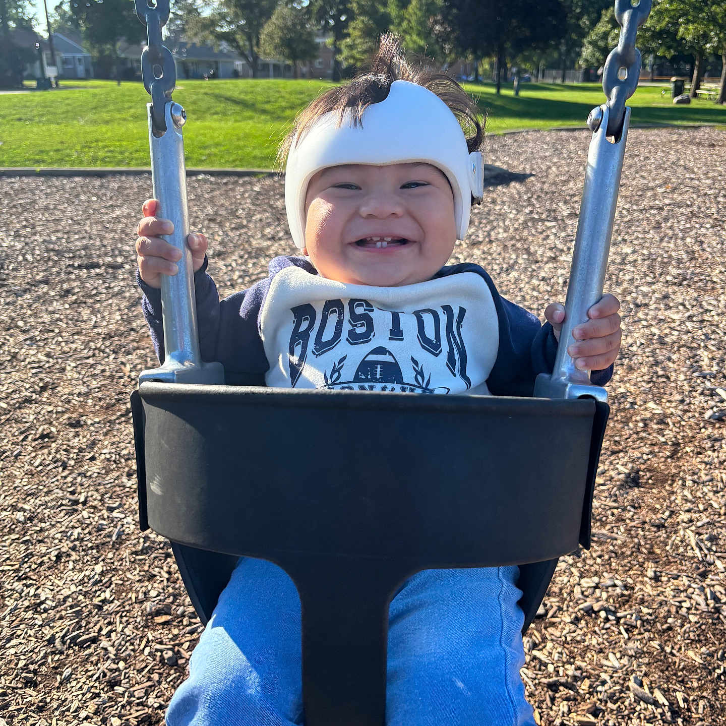 Eliot joined the competition — help win amazing prizes! child, clothing, daytime, fun, grass, happy, helmet, holding, metal, outdoor, park, person, playground, seat, smile, sunshine, swing, toddler, trees, woodchips
