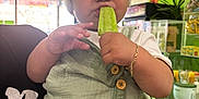 Eliot joined the competition — help win amazing prizes! bracelet, bright_colors, button, child, clothing, counter, face, food, green_popsicle, hand, helmet, indoor, person, plant, popsicle, shorts, snack, store, toddler, window