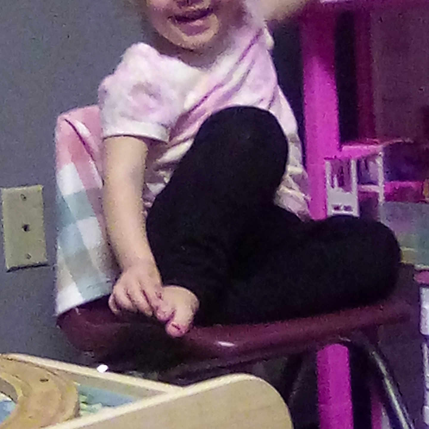 Marigold is registered to the contest to win money with this photo: background, black_pants, chair, child, clothing, electric_outlet, furniture, hair, happy, indoor, legs, person, pink, playful, room, smiling, table, toddler, toy, wood