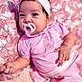 baby, pacifier, pink_clothing, headband, bow, infant, blanket, floral_pattern, cute, child, portrait, lying_down, soft_texture, indoors, adorable, skin, hand, face, eyes, sleepwear
