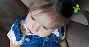 Jazlyn is registered to the contest to win money with this photo: baby, child, toddler, sitting, couch, portrait, sleepy, closed_eyes, hair_bows, green_bows, denim, overalls, floral_shirt, indoor, furniture, face, hands, photography, cute, casual_clothing