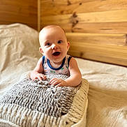 Aïden a rejoint le concours — aidez-le/la à gagner de superbes lots ! baby, bed, child, cozy, cushion, cute, expression, happy, home, indoors, infant, knitted_pillow, person, portrait, resting, sleepwear, smiling, soft_light, toddler, wooden_wall