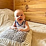 baby, bed, child, cozy, cushion, cute, expression, happy, home, indoors, infant, knitted_pillow, person, portrait, resting, sleepwear, smiling, soft_light, toddler, wooden_wall
