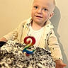 child, toddler, birthday_cake, number_candle, cake, celebration, smile, face, young_child, clothing, party, hand, eyes, shirt, indoors, person, happy, food, sweet, dessert