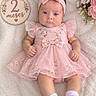 baby, baby_shoes, bow, child, cute, fashion, floral, flowers, headband, indoor, infant, lying_down, milestone_photo, pink_dress, portrait, rug, smiling, socks, top_down, two_months