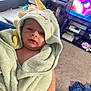 Caspian joined the competition — help win amazing prizes! baby, child, towel, hooded_towel, dinosaur, indoor, living_room, television, aquarium, carpet, clothing, person, soft_texture, cute, young_child, blanket, furniture, toy, relaxing, home