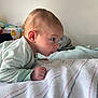 Caspian is registered to the contest to win money with this photo: baby, child, infant, blanket, bed, striped_blanket, toy, soft_toy, person, face, head, hand, curious, sleepwear, indoors, wall, pillow, couch, light, portrait