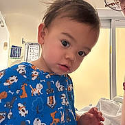 Arturo is registered to the contest to win money with this photo: toddler, child, blue_shirt, animal_print, indoor, curious, face, person, portrait, hair, hand, bed, blanket, adult, glasses, window, daylight, skin, expression, candid