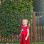 casual_clothing, child, daylight, face_paint, fence, girl, grass, greenery, hair_clip, happy, minnie_mouse, nature, outdoor, playful, portrait, red_dress, smiling, sneakers, socks, standing