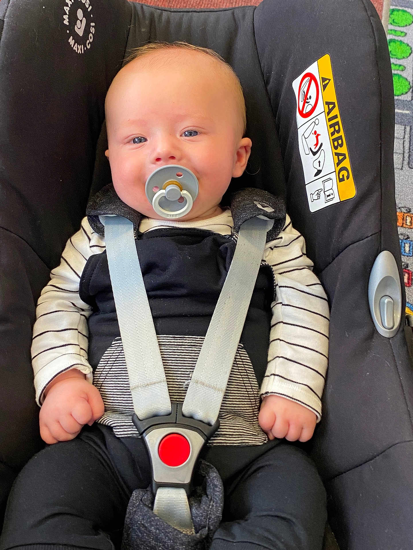 Hunter-Eli is registered to the contest to win money with this photo: baby, pacifier, car_seat, child, infant, straps, seatbelt, black_clothing, striped_shirt, safety, comfort, indoors, cute, smiling, young_child, face, hands, head, car_safety, happiness