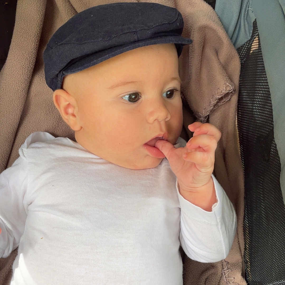 Aaron a rejoint le concours — aidez-le/la à gagner de superbes lots ! baby, black_pants, blanket, cap, child, clothing, curious, cute, face, finger, hand, headwear, indoor, infant, lying_down, portrait, soft_texture, stroller, white_shirt, young