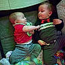 Princeston is registered to the contest to win money with this photo: baby, infant, child, playpen, blanket, clothing, smiling, face, interaction, indoor, cute, toddler, happy, lying_down, person, fabric, cozy, sibling, playtime, casual