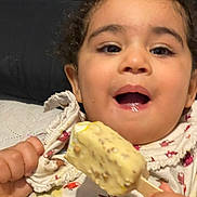 Neila participe au concours pour gagner de l'argent avec cette photo : bird_print, child, clothing, comfort, couch, curly_hair, delicious, face, food, hand, happy, ice_cream, indoor, mouth_open, pattern, sitting, smiling, snack, sweet, toddler