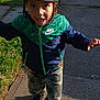 boy, camo_pants, cap, casual_clothing, child, daylight, expression, footwear, grass, happy, hat, jacket, nature, nike, outdoor, person, playful, running, sidewalk, sunlight