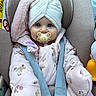baby, blue_eyes, car_seat, child, closeup, cute, floral_pattern, fuzzy, hat, indoor, infant, jacket, pacifier, pink, portrait, seatbelt, straps, turban, warm_clothing, winter_clothing
