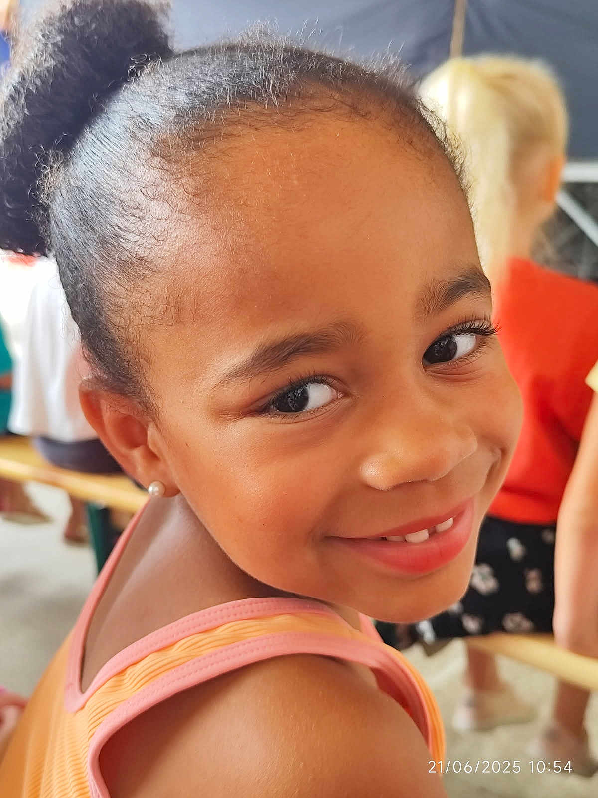 Joséphine participe au concours pour gagner de l'argent avec cette photo : child, girl, smile, face, portrait, happy, hair_puff, earrings, bench, people, indoor, casual_clothing, shoulder, skin, eyes, childhood, candid, daylight, person, young