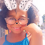 Joséphine a rejoint le concours — aidez-le/la à gagner de superbes lots ! blue_dress, bunny_ears, child, curly_hair, cute, daytime, digital_filter, eyewear, face, fashion, glasses, hand, happy, nature, outdoor, person, portrait, smiling, sparkles, sunlight