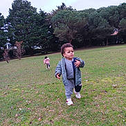 Hector participe au concours pour gagner de l'argent avec cette photo : child, toddler, park, grass, trees, jacket, tracksuit, sneakers, outdoor, playing, nature, greenery, walking, running, casual_clothing, daytime, two_children, field, young_child, activity
