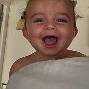 Gabriel participe au concours pour gagner de l'argent avec cette photo : baby, child, smiling, curly_hair, blanket, indoors, face, happy, portrait, person, skin, head, expression, cute, young, infant, room, light, lamp, warm