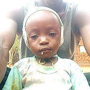Richard participe au concours pour gagner de l'argent avec cette photo : child, toddler, person, adult, hat, face, outdoor, rural, mud_wall, shirt, stain, closeup, portrait, headwear, skin, expression, parent, nature, daylight, photography