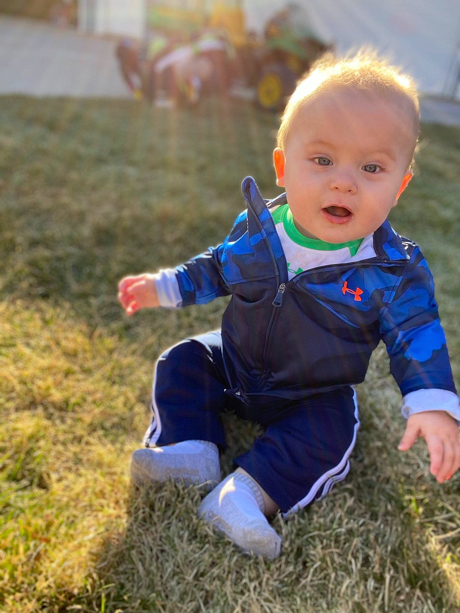 Easton is registered to the contest to win money with this photo: baby, blue, child, electric_blue, grass, leaf, leg, outerwear, people, person, plant, play, sitting, smile, toddler