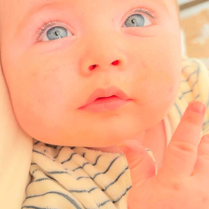 Imran participe au concours pour gagner de l'argent avec cette photo : baby, infant, blue_eyes, close_up, face, hand, striped_clothing, soft_lighting, cute, child, portrait, skin, young, looking_up, expression, person, indoors, newborn, adorable, curious