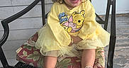 London joined the competition — help win amazing prizes! child, toddler, girl, smiling, yellow_sweater, winnie_the_pooh, pink_bow, chair, cushion, wooden_floor, porch, happy, sitting, shoes, casual_clothing, cute, outdoor, daylight, person, portrait