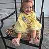 child, toddler, girl, smiling, yellow_sweater, winnie_the_pooh, pink_bow, chair, cushion, wooden_floor, porch, happy, sitting, shoes, casual_clothing, cute, outdoor, daylight, person, portrait