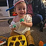 London is registered to the contest to win money with this photo: toddler, child, toy, playing, carpet, man, beard, indoor, smiling, happy, sitting, clothing, dog_paw, floor, furniture, household, person, hat, family, colorful