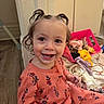 London is registered to the contest to win money with this photo: toddler, child, smiling, pigtails, indoor, floor, wooden_floor, clothing, basket, messy, hair, playful, happy, pink, orange_outfit, person, young_child, cute, baby, expression