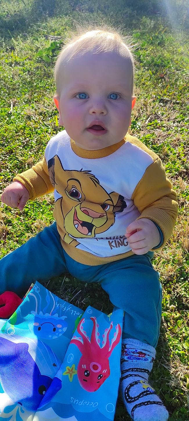 Matteo a rejoint le concours — aidez-le/la à gagner de superbes lots ! baby, baby_toddler_clothing, blue, child, cool, facial_expression, fun, grass, happy, leisure, people_in_nature, person, plant, play, recreation, sitting, sleeve, summer, t_shirt, toddler