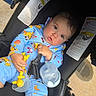 Dariel Frontela joined the competition — help win amazing prizes! baby, child, stroller, blue_onesie, toy, baby_bottle, cartoon_print, curious, infant, outside, seat_belt, safety_warning, playful, hand, face, cute, expression, young, comfort, daylight