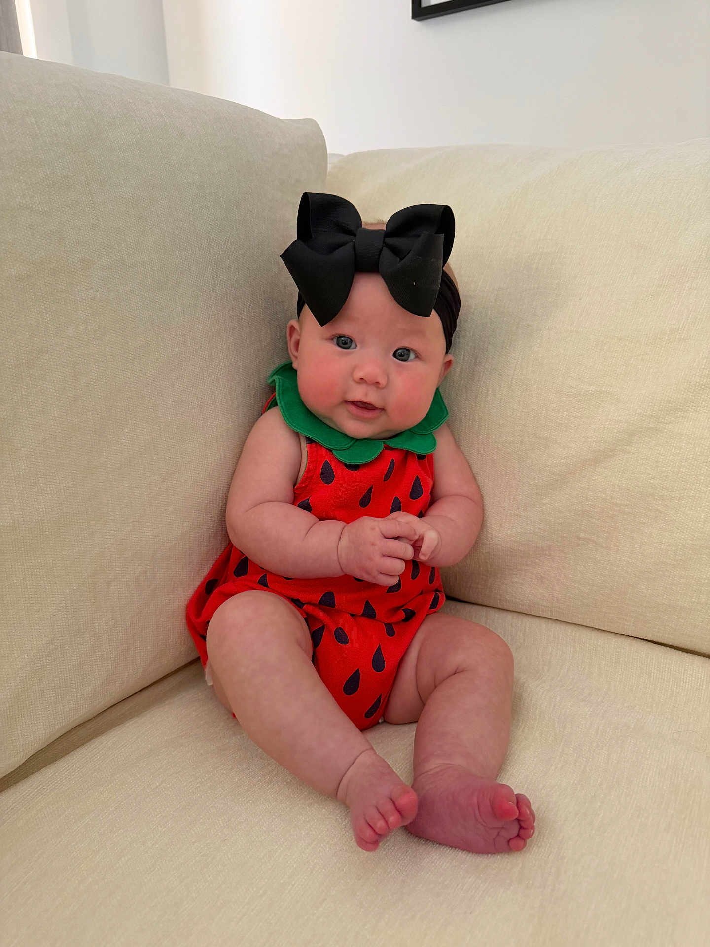 Emersyn joined the competition — help win amazing prizes! baby, infant, watermelon_romper, black_bow, headband, couch, sofa, living_room, sitting, chubby_cheeks, barefoot, toes, cute, portrait, pink_cheeks, blue_eyes, plush_fabric, home_interior, soft_lighting, adorable