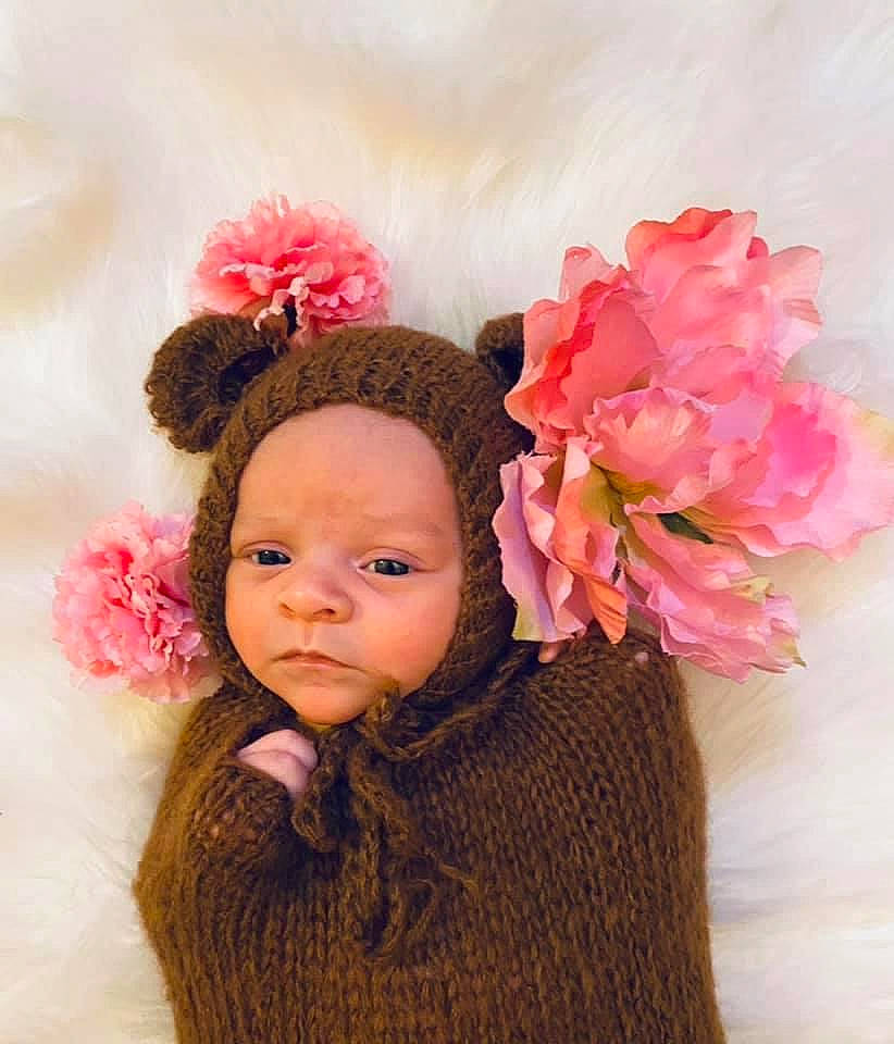 Everleigh Grace is registered to the contest to win money with this photo: baby, baby_toddler_clothing, cap, costume_hat, cut_flowers, eyelash, flower, hair_accessory, hairstyle, happy, headband, headgear, headpiece, knit_cap, magenta, peach, person, petal, pink, textile