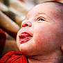 baby, face, tongue, red_clothing, closeup, skin, cheek, head, expression, infant, newborn, portrait, cute, child, human, person, soft_background, playful, young, smiling