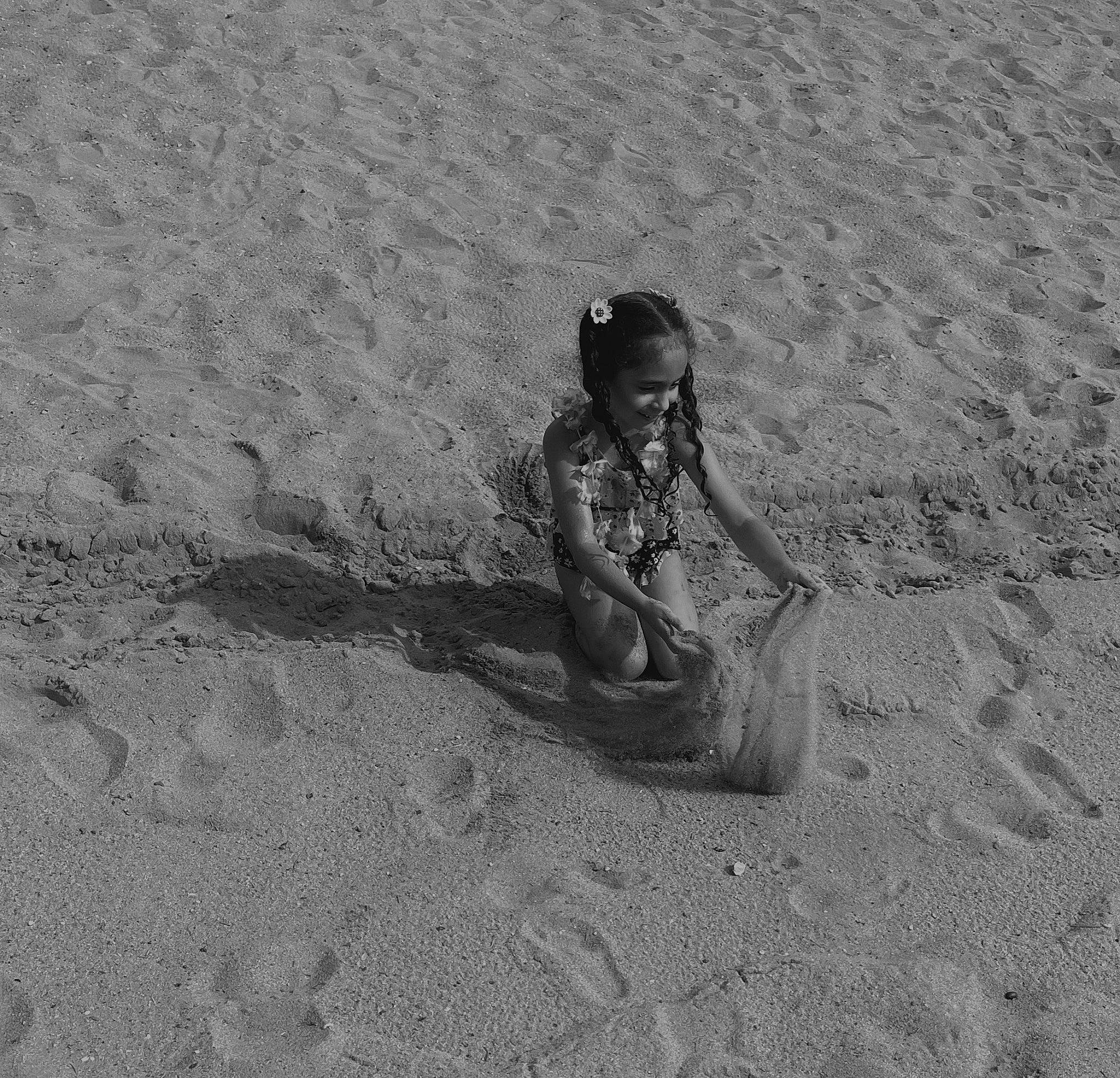 Valentina is registered to the contest to win money with this photo: aeolian_landform, barefoot, beach, body_of_water, child, foot, fun, human_leg, joy, landscape, monochrome, monochrome_photography, natural_environment, people_in_nature, person, play, recreation, sand, shadow, sitting