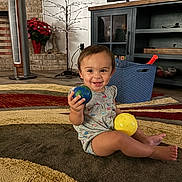 Azalea joined the competition — help win amazing prizes! toddler, child, smiling, indoor, rug, toy, ball, basket, living_room, fan, plant, furniture, floor, clothing, cute, happy, person, play, home, decor