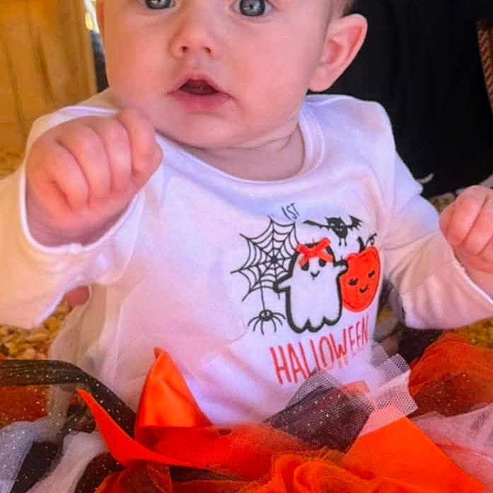 Madilynn is registered to the contest to win money with this photo: baby, celebration, child, clothing, corn, costume, cute, expression, festive, ghost, halloween, hand, indoors, infant, person, portrait, pumpkin, sitting, striped_socks, tulle