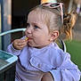 Evelyn is registered to the contest to win money with this photo: toddler, child, blue_eyes, pink_sunglasses, light_purple_sweatshirt, snack, hand, hair_tie, pony_tail, table, outdoor, green_carpet, face, person, sitting, eating, casual_clothing, daylight, cute, portrait
