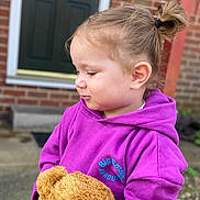 Evelyn joined the competition — help win amazing prizes! brick_wall, casual_clothing, child, cute, daylight, door, front_yard, happy_moment, holding, outdoor, person, portrait, purple_hoodie, side_view, small_pony_tail, soft_toy, teddy_bear, toddler, toy, young_child