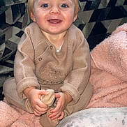 Kylo joined the competition — help win amazing prizes! toddler, child, smiling, blue_eyes, blonde_hair, beige_outfit, holding_foot, pink_blanket, cozy, indoor, couch, patterned_cushion, pet, dog_spot, happy, portrait, cute, baby_clothes, hands, feet