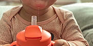 Amira is registered to the contest to win money with this photo: baby, bottle, child, closeup, clothing, cute, drool, eyelashes, face, fingertips, hands, happy, indoor, long_sleeve, person, sippy_cup, sitting, smiling, water, young_child