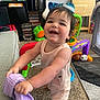 baby, ball, carpet, chair, child, face, furniture, happy, home, indoor, person, play_area, purple_cloth, rug, shorts, sleeveless_shirt, smiling, socks, toddler, toys