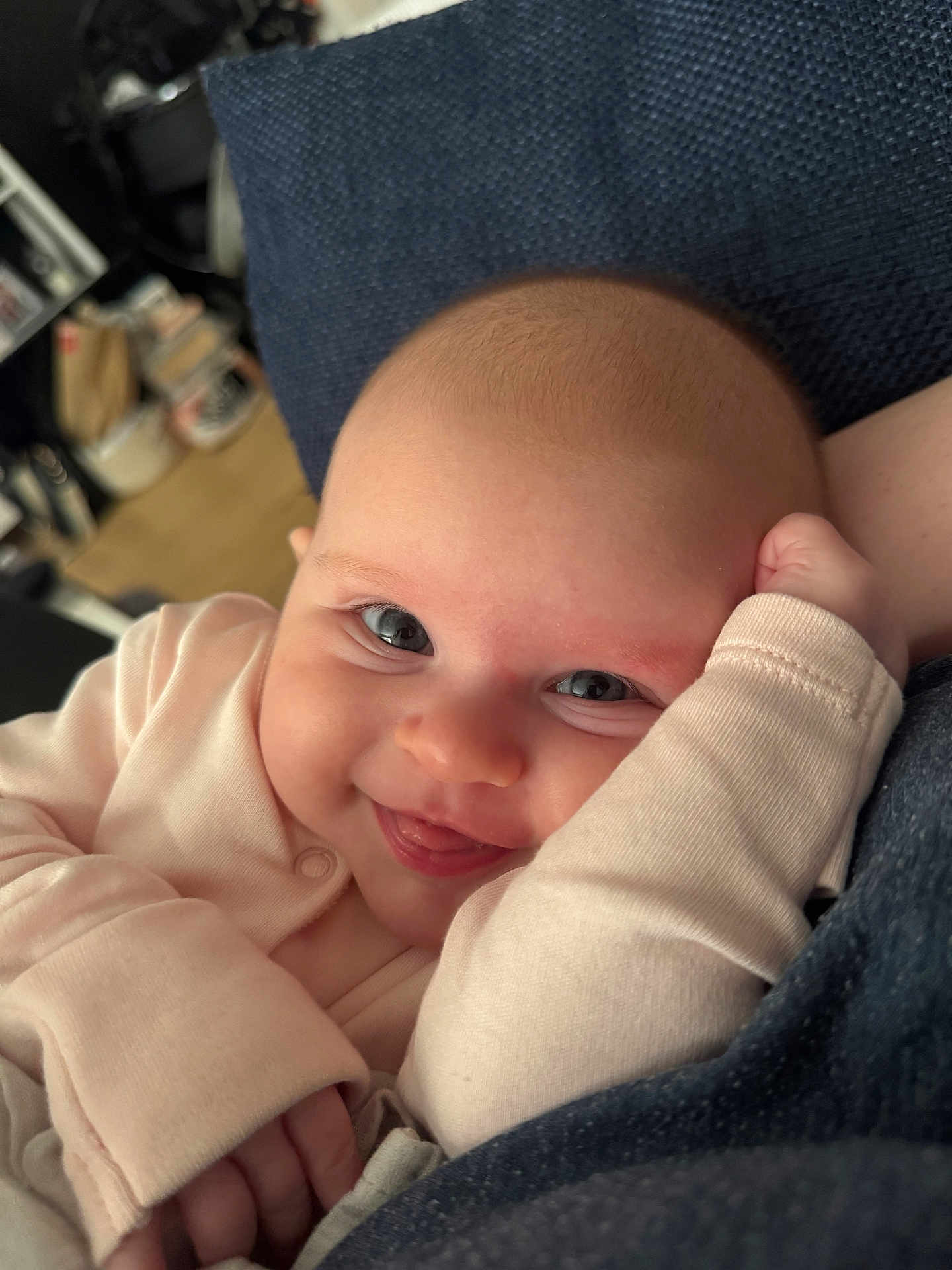 Ava is registered to the contest to win money with this photo: baby, smiling, tongue_out, close_up, infant, cute, person, indoor, cushion, clothing, face, head, skin, hand, expression, happy, newborn, cozy, texture, portrait