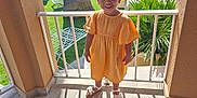 Aurora is registered to the contest to win money with this photo: child, girl, orange_dress, balcony, sunlight, shadow, pool, greenery, tree, plant, sandals, smile, outdoor, daylight, railing, floor, happy, person, summer, vacation